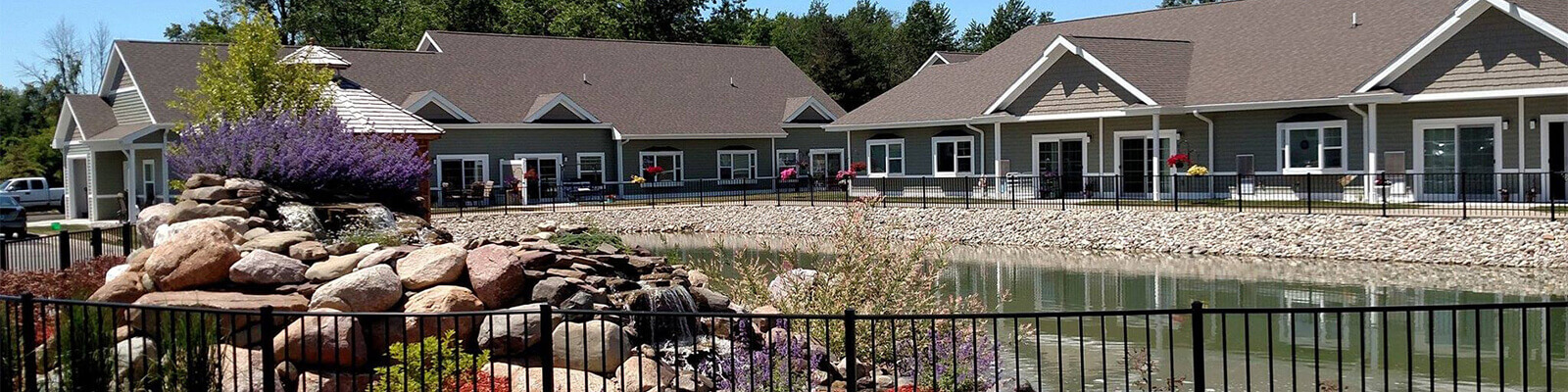 Traditions of Saginaw Senior Living community brown homes with a pond in front of them