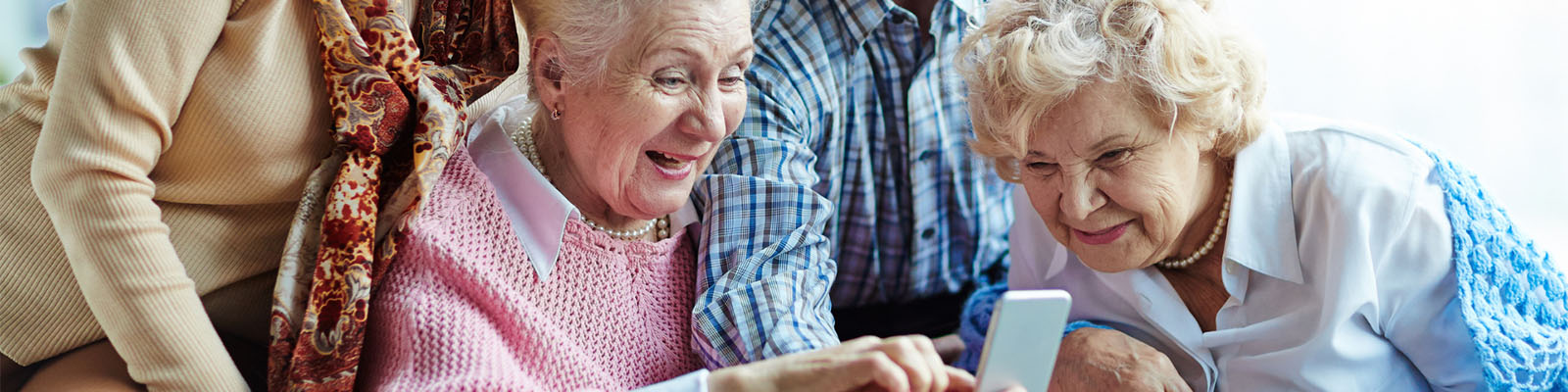 Elderly female senior living residents smiling and looking at photos on a mobile phone