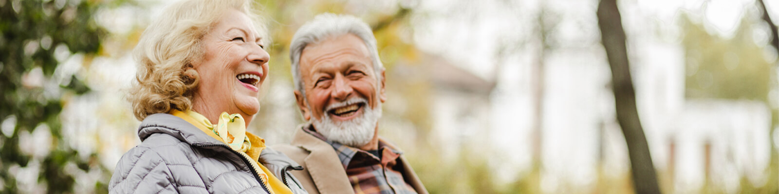 A senior man and woman laughing together outside looking at nature