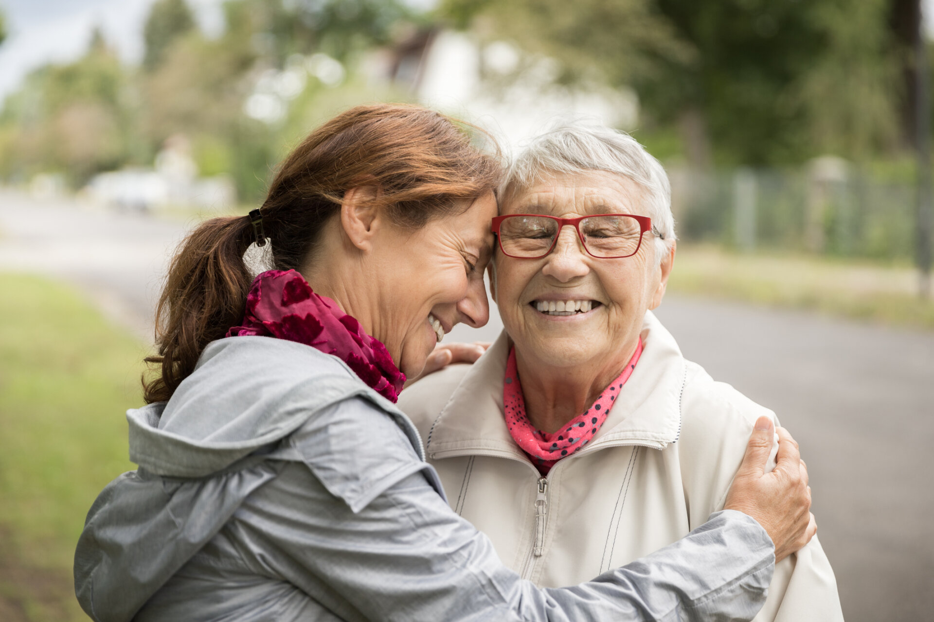 A senior man and woman sitting together on a park bench smiling and laughing together